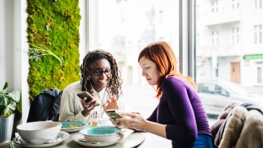 カフェでスマートフォンを操作する2人の女性の写真