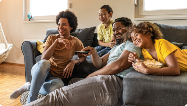 A family relaxing on sofa and enjoying TV shows with snacks